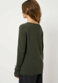 Mørkegrøn, langærmet sweater med en afslappet pasform, rund halsudskæring og ribbede detaljer ved ærmerne. Blød tekstur, falder under hoften.