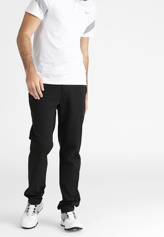 Černé polyesterové kalhoty s rovnými nohavicemi, kombinované s bílým polo tričkem se šedými akcenty a bílými sportovními botami.