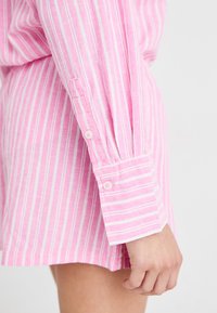 Camisa de manga longa às riscas rosa e branca com punhos abotoados. Tecido suave com um corte descontraído, apresentando um padrão texturizado sutil.