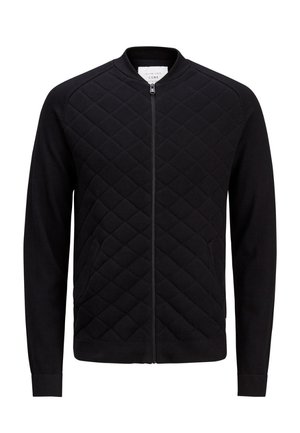 Veste noire matelassée à fermeture éclair avec manches longues et col, poignets et ourlet côtelés, présentant un motif de coutures en losange à l'avant.