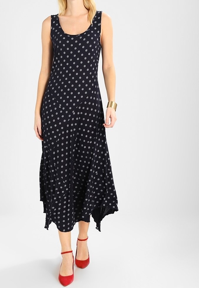 Black dress with a scoop neckline, featuring a white floral pattern, uneven hem, and made from a soft fabric. Worn with red ankle-strap heels.