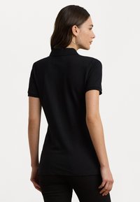Svart polo skjorte med klassisk krage, korte ermer og en tettsittende design. Glatt tekstur, skreddersydd snitt, ingen synlige mønstre eller akenter.