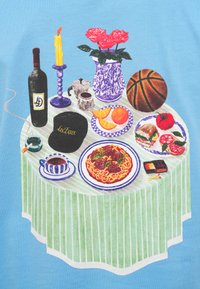 Τραπέζι στρωμένο με πράσινο ριγέ τραπεζομάντιλο, που περιλαμβάνει ένα μπουκάλι κρασί, κερί, λουλούδια, πιάτο με ζυμαρικά, φρούτα και μια μπάλα καλαθοσφαίρισης.