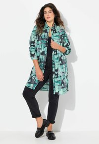 Leichtes, gemustertes Hemd in Teal- und Schwarzfarben, mit Knopfleiste und langen Ärmeln, kombiniert mit schwarzen Skinny Jeans und Schuhen.