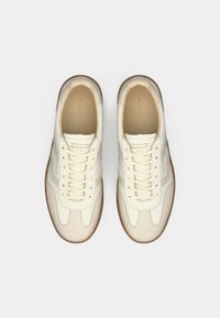 Weiße Leder-Sneaker mit strukturierten beigen Wildlederakzenten, runder Zehenpartie und Schnürdesign. Weiche Innenauskleidung und Gummisohle.