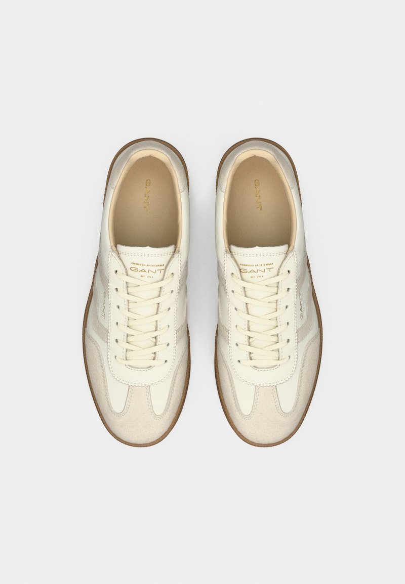 Weiße Leder-Sneaker mit strukturierten beigen Wildlederakzenten, runder Zehenpartie und Schnürdesign. Weiche Innenauskleidung und Gummisohle.