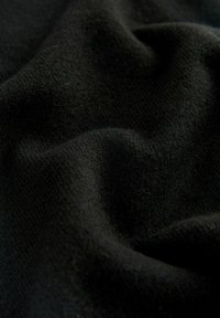 Schwarzer Stoff mit einer glatten, strukturierten Oberfläche, die subtile Variationen im Gewebe aufweist. Das Material erscheint weich und leicht flauschig.