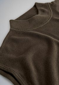 Jersey marrón de punto sin mangas con cuello alto de canalé y textura de punto fina, extendido sobre una superficie clara.