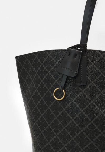 Black leather tote bag featuring a textured surface, geometric pattern, and a gold metal ring accent. Adjustable black handle included.