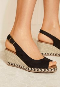 Fekete velúr wedge szandál, peep toe és slingback pánttal, fonott juta talppal, fekete és fehér díszítéssel.