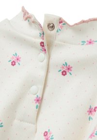 Weißer gerippter Stoff mit rosa Punkten und kleinen Blumenmustern in Rosa und Türkis. Verfügt über einen rüschenbesetzten Halsauschnitt und Druckknöpfe.