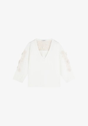 Haut blanc à manches longues avec un col en V, broderies florales sur les épaules et un panneau arrière texturé. Tissu doux.