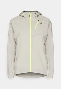 Chaqueta con capucha gris claro, cremallera amarilla neón y bolsillo en el pecho, con cordones ajustables en la capucha y puños elásticos.