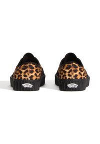 Par de zapatillas Vans con estampado de leopardo y suelas de goma negras vistas desde atrás sobre un fondo blanco.