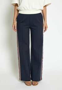 Navy wide-leg trousers made of smooth fabric, featuring side stripes in red, white, and blue. Detailed with front pleats.