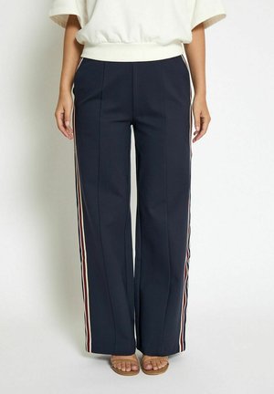Navy wide-leg trousers made of smooth fabric, featuring side stripes in red, white, and blue. Detailed with front pleats.