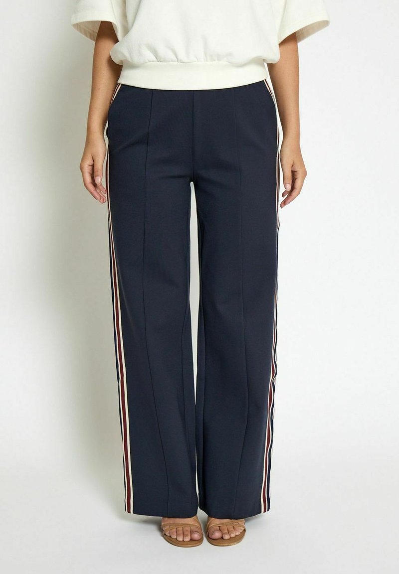 Navy wide-leg trousers made of smooth fabric, featuring side stripes in red, white, and blue. Detailed with front pleats.