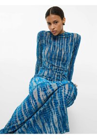 Robe longue et ajustée à motif tie-dye bleu et blanc, avec manches longues et col montant, confectionnée dans un tissu léger et texturé.