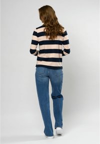 Gestreepte langemouwen top in navy en blush met een ronde onderkant, gecombineerd met ontspannen lichte spijkerbroek en witte sneakers.