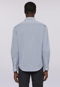 Košile s dlouhými rukávy v modro-bílých pruzích, s límečkem na knoflíky a zakřiveným lemem. Vyrobena z lehkého materiálu s hladkou texturou.