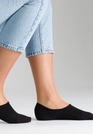 Schwarze, niedrig geschnittene Socken aus weichem Stoff. Sie haben eine glatte Textur und ein einfaches Design, das den Fuß teilweise bedeckt. Denim-Jeans sind sichtbar.