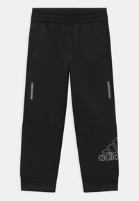 Mustat urheiluhousut, jotka on valmistettu sileästä kankaasta, jossa on elastinen vyötärö, kaksi sivutaskua ja valkoinen Adidas-logo vasemmassa alareunassa.