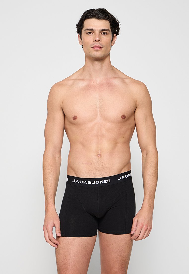 Junger Mann mit kurzen dunklen Haaren steht frontal und trägt schwarze boxer briefs mit Jack & Jones Marke vor einem schlichten hellen Hintergrund.
