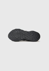 Svart sportsko såle med teksturerte, hevede mønstre for grep. Har en sentral Nike-logo. Rund form med en glatt overflate.