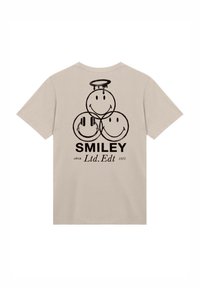 Beige T-shirt featuring three smiley faces, one with headphones, one with a halo, and the text "SMILEY Ltd.Ed 1972" in black.
