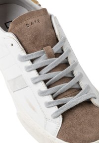 Sneaker bianco con accenti in suede marrone, lacci grigi e suola testurizzata. Presenta una linguetta con il marchio "D.A.T.E." in rilievo.