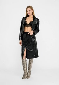 Črno usnjeno krajšo jakno prek črnega čipkastega braletnega topa, v kombinaciji s črno sijočo krilo s sprednjim zarezom; poudarjeno z metalik škornji z vzorcem kače, ki segajo do kolen.