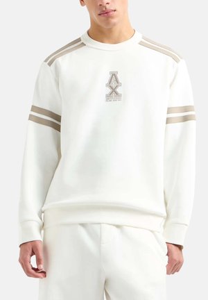 Sweatshirt blanc avec un col rond, rayures beige clair sur les épaules et un logo sur la poitrine. Texture douce, coupe décontractée.