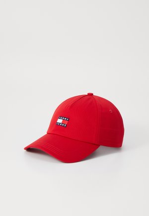 Cappellino da baseball rosso con visiera curva, caratterizzato da un patch logo rettangolare in bianco, nero e blu che reca la scritta "TOMMY JEANS" sul davanti.