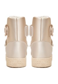 Stivaletti alla caviglia in raso beige con suola in gomma tan testurizzata. Presentano due strap in velcro e una parte superiore liscia con bordi arrotondati.
