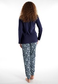 Marineblauwe long-sleeve top gecombineerd met bloemenpatroon broek in blauw, wit en groen. Zachte stof; comfortabele pasvorm; broek tot de enkels.