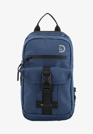 Mochila de tela azul con detalles en negro, una solapa frontal, bolsillo con cremallera y un broche de plástico. Presenta un logo en la parte delantera. Dos asas superiores.