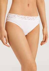 Panties de algodón blanco con una cinturilla de encaje en forma de ondas, con una textura de tela suave y sin patrones visibles. Corte clásico de braga.