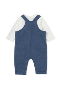 Baby-Overalls aus blauer Baumwolle mit einem weichen weißen Langarm-Body darunter. Mit verstellbaren Trägern und umgeschlagenen Säumen an den Beinen.