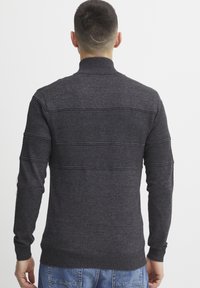 Pull en maille gris charbon avec un col montant, des rayures horizontales texturées, des poignets et un ourlet côtelés. Fabriqué en matière tricotée douce.