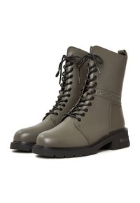 Khaki veterschoenen voor gevechtsdoeleinden, gemaakt van glad leer met een gestructureerde banddetail, zwarte veters en een robuuste rubberen zool.