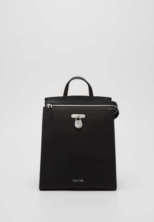 Black Calvin Klein handbag with top handle, silver zipper, and a front silver lock detail on a plain background.