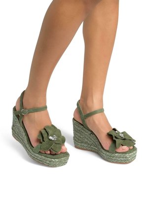 Sandali con zeppa in suede verde, con un'accento floreale, piattaforma in juta intrecciata e cinturino alla caviglia. Presentano un dettaglio in strass sul fiore.