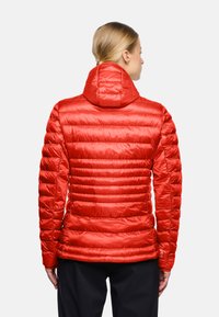 Giacca a vento rossa con motivo a righe orizzontali trapuntate, cappuccio aderente e texture liscia e lucida. Presenta polsini elasticizzati e un design elegante.