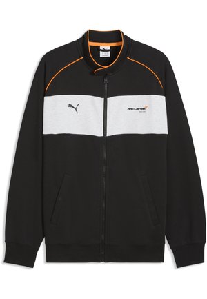 Schwarze Jacke mit Reißverschluss, grauem Bruststreifen, oranger Paspelierung an den Schultern, Puma-Logo links und McLaren Racing-Logo rechts.