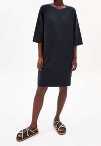 Granatowa sukienka bawełniana z okrągłym dekoltem, rękawami o długości trzech ćwierci i prostym krojem. Połączona z czarnymi sandałami z białymi akcentami ze sznurka.