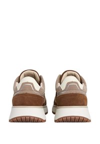 Un paio di sneakers marroni e beige con suole bianche spesse, viste da dietro, che mostrano colli imbottiti e suole in gomma testurizzate.