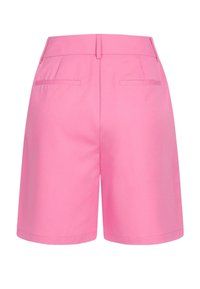Pantaloni corti rosa con un design su misura, caratterizzati da due tasche posteriori e una texture liscia. La vita è semplice con un taglio dritto sulle gambe.
