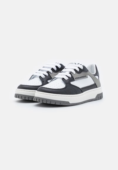 Le sneakers presentano una tomaia in pelle nera con accenti bianchi e grigi, una punta perforata, lacci bianchi e una suola in gomma testurizzata.