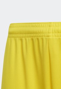 Nahaufnahme eines leuchtend gelben Elastikbundes mit doppelt genähten Nähten auf glattem Stoff.