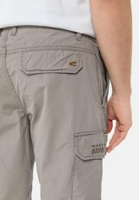 Graue Cargo-Hosen aus leichtem Stoff, mit seitlichen und hinteren Taschen, genähten Details und einem geprägten Logo an der Seite.